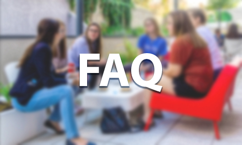 An image of students gathered around a table that has been blurred with the letters FAQ in the foreground