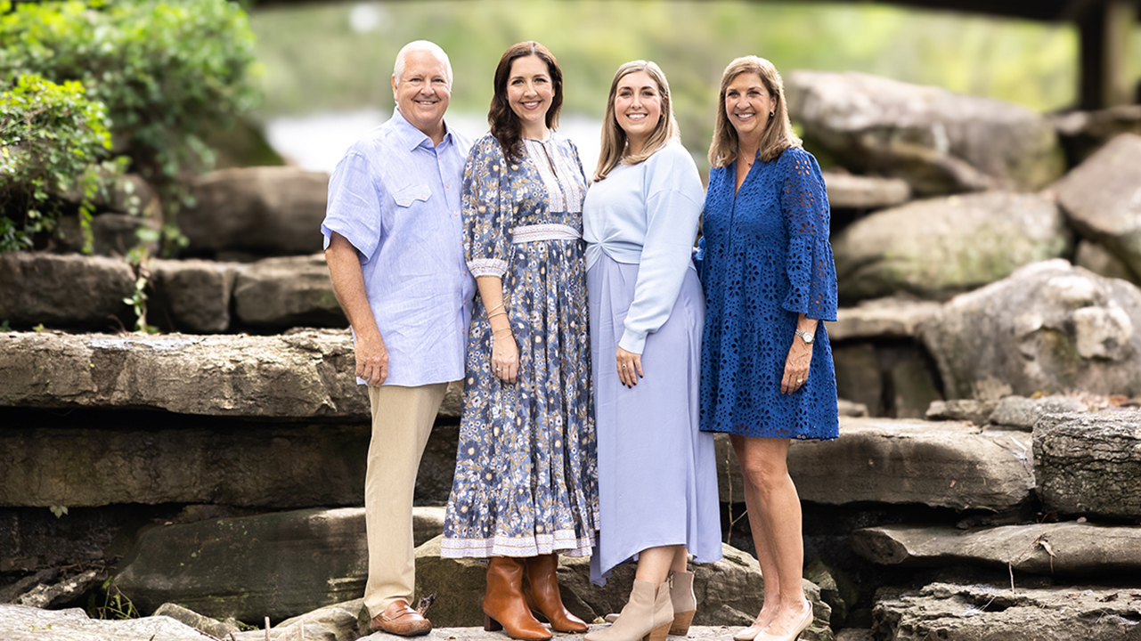 4 adults standing together outside