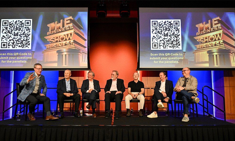 Six men sitting on stage