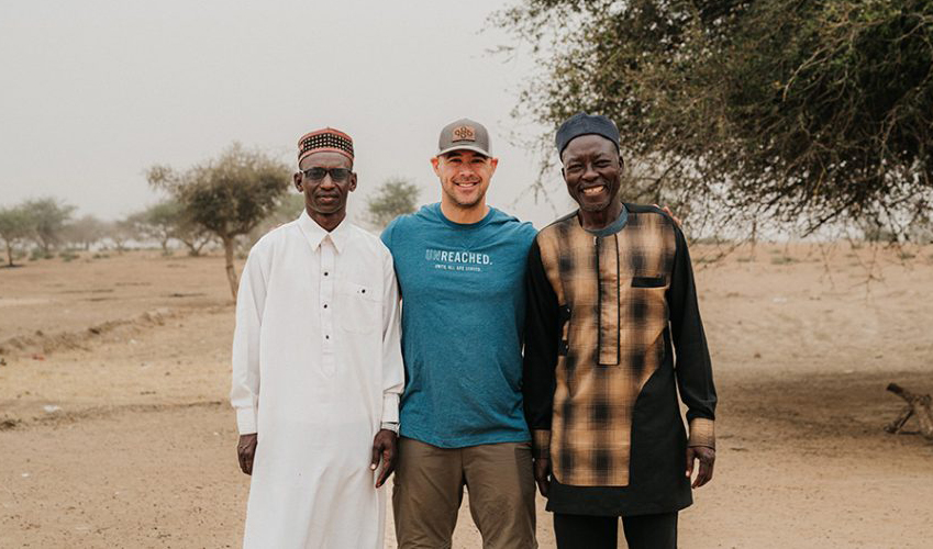 Alumnus Matt Letourneau 3 men standing together in field