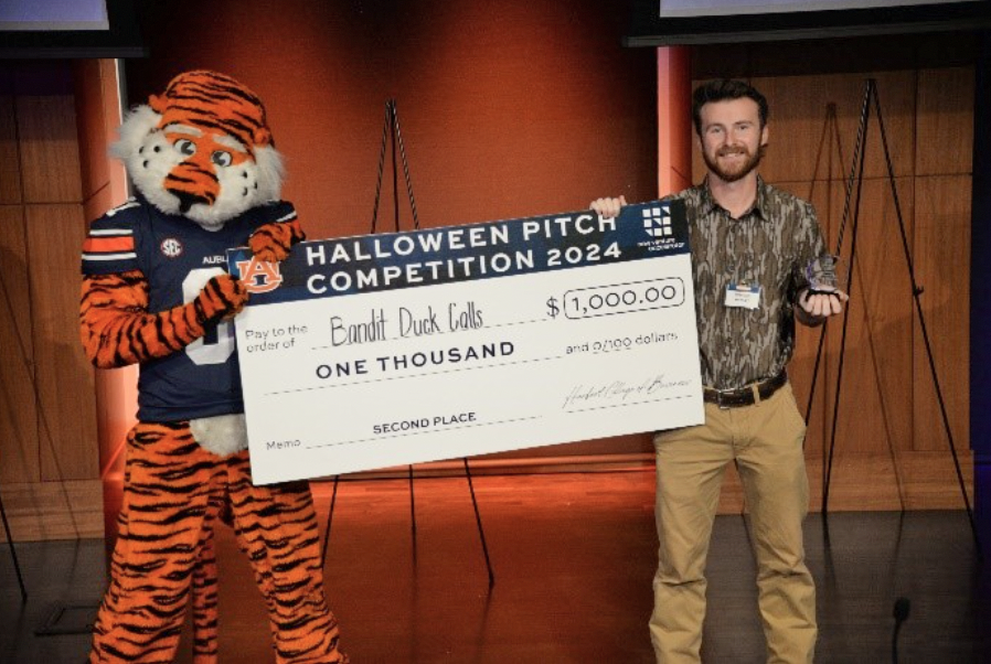 Pitch winner holding check with Aubie