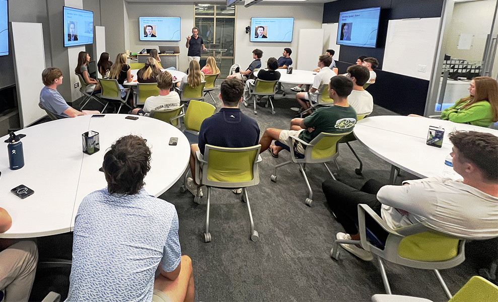 Students sitting in class with speaker talking