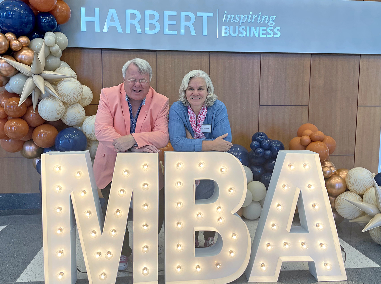 Sarah and Peter Stanwick Sarah and Peter Stanwick behind MBA lit sign