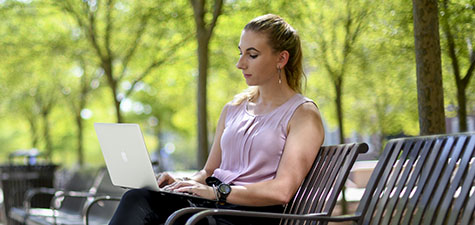Student sitting outdoors working on computer